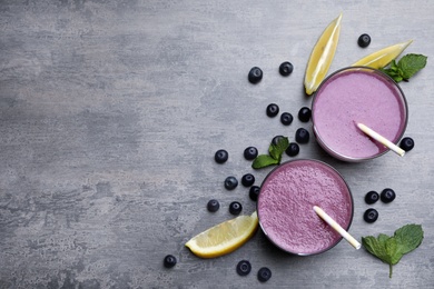 Photo of Flat lay composition with tasty acai drink, berries and space for text on grey table