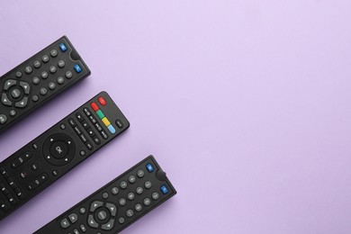 Photo of Remote controls on violet background, flat lay. Space for text