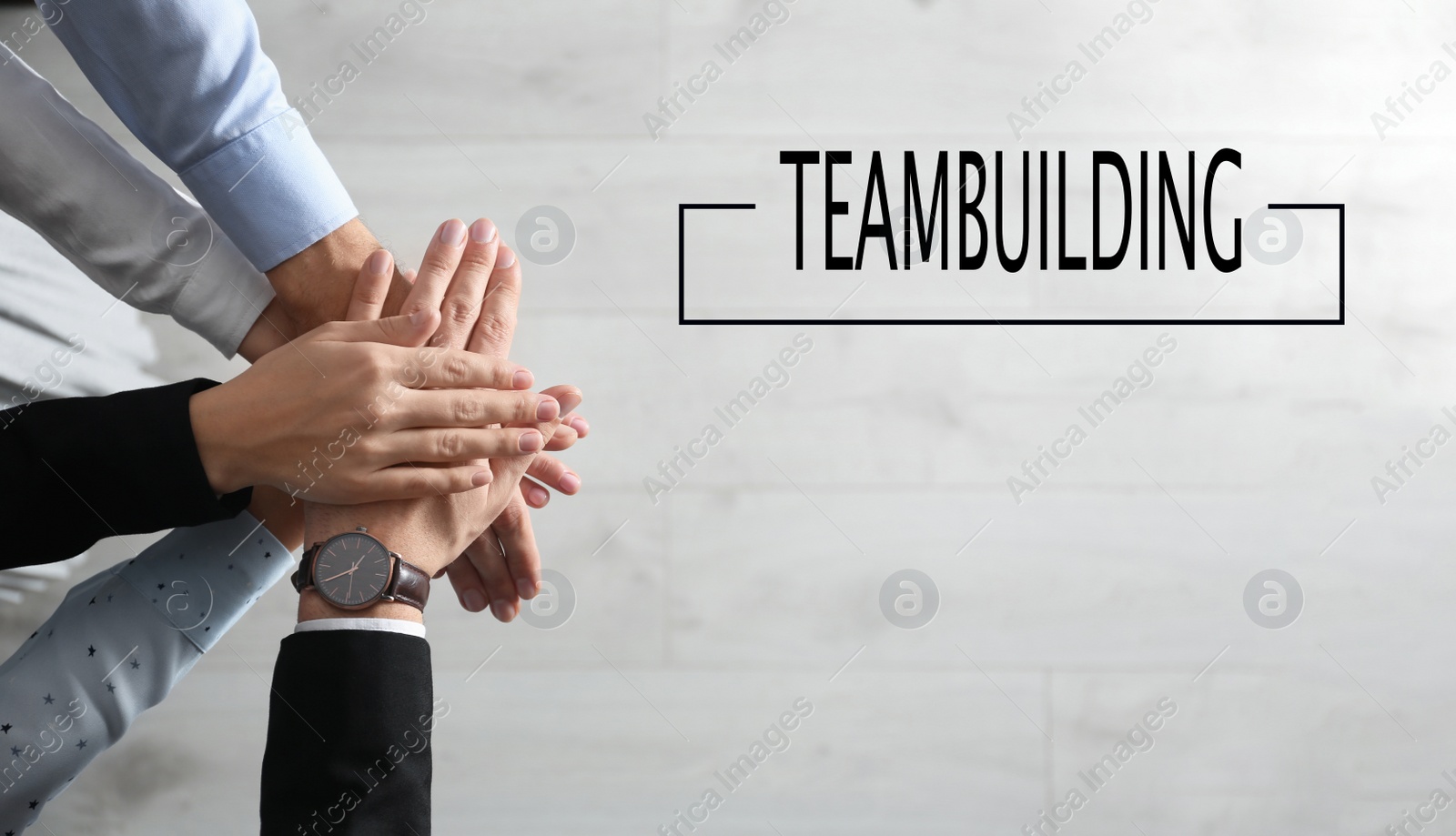 Image of People holding hands together over light wooden background, top view. Team building