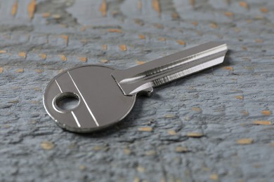 One key on grey wooden table, closeup