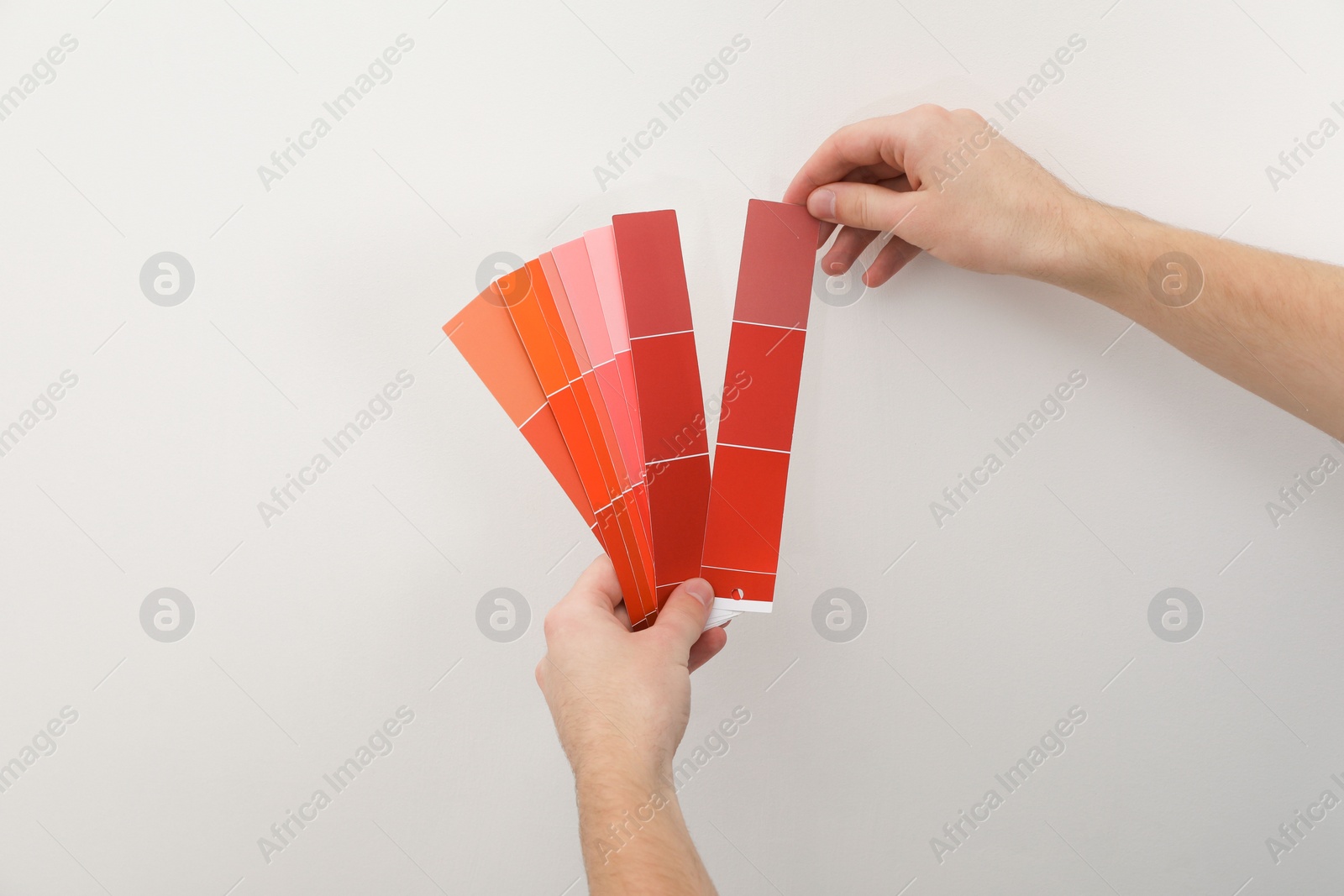 Photo of Man with palette choosing color for painting wall indoors, closeup. Interior design