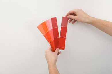 Photo of Man with palette choosing color for painting wall indoors, closeup. Interior design