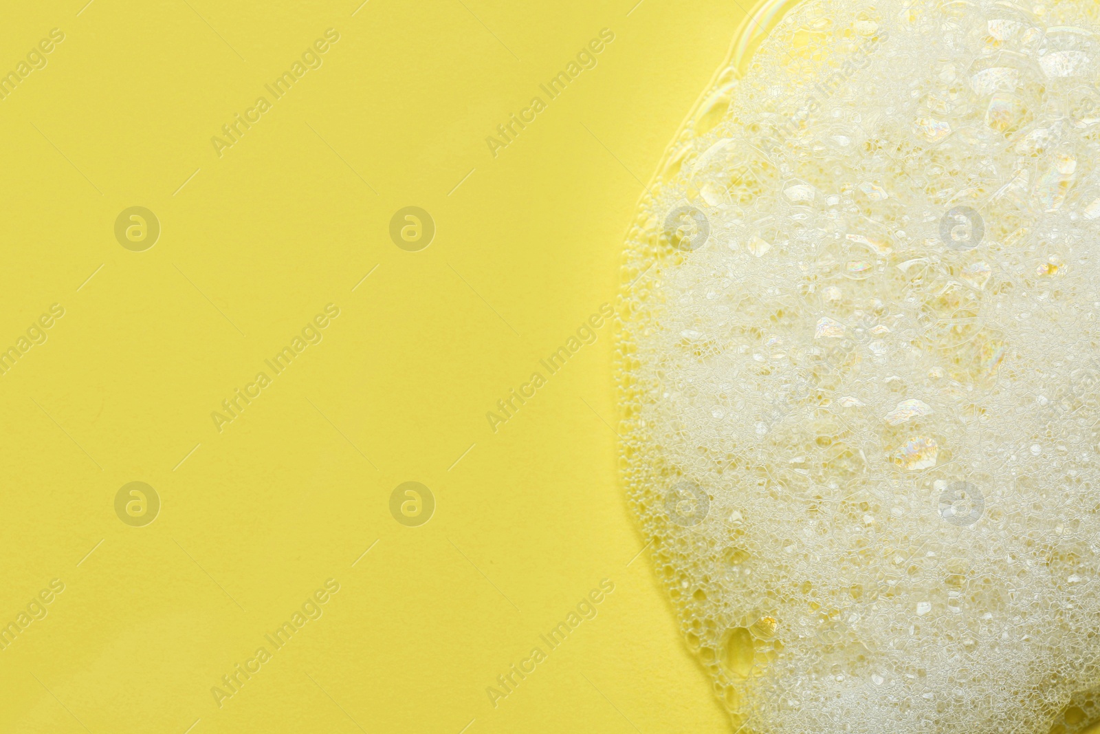 Photo of Fluffy bath foam on yellow background, top view. Space for text