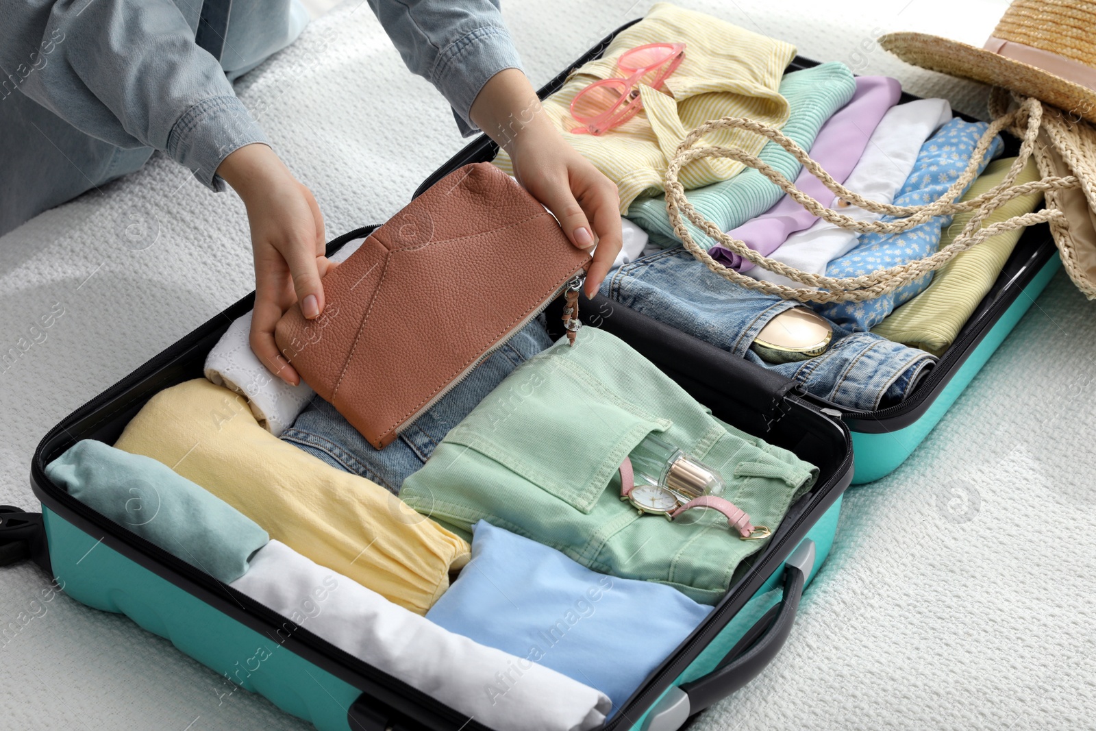 Photo of Woman packing suitcase for trip on bed, closeup