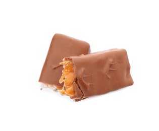 Photo of Broken chocolate bar with caramel, nuts and nougat isolated on white, top view