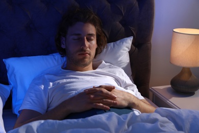 Photo of Handsome young man sleeping with book on pillow at night. Bedtime