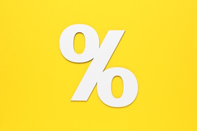 Photo of Paper percent symbol cutout on yellow background, top view