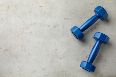 Photo of Blue dumbbells on light grey table, flat lay. Space for text