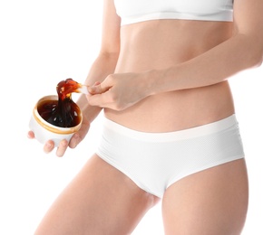 Photo of Young woman holding hot wax on white background, closeup. Epilation procedure
