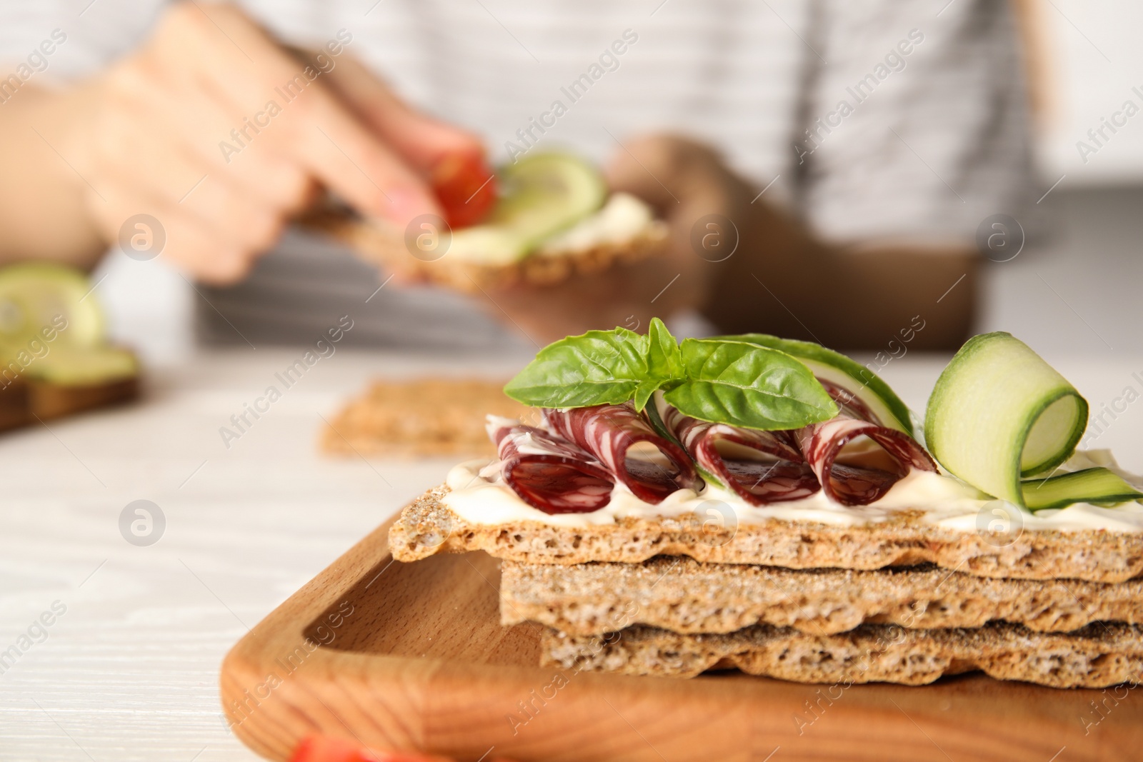 Photo of Fresh rye crispbreads with salami, cream cheese and cucumber on table, closeup