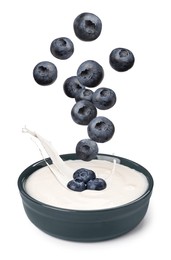 Image of Delicious ripe blueberries falling into bowl with yogurt on white background