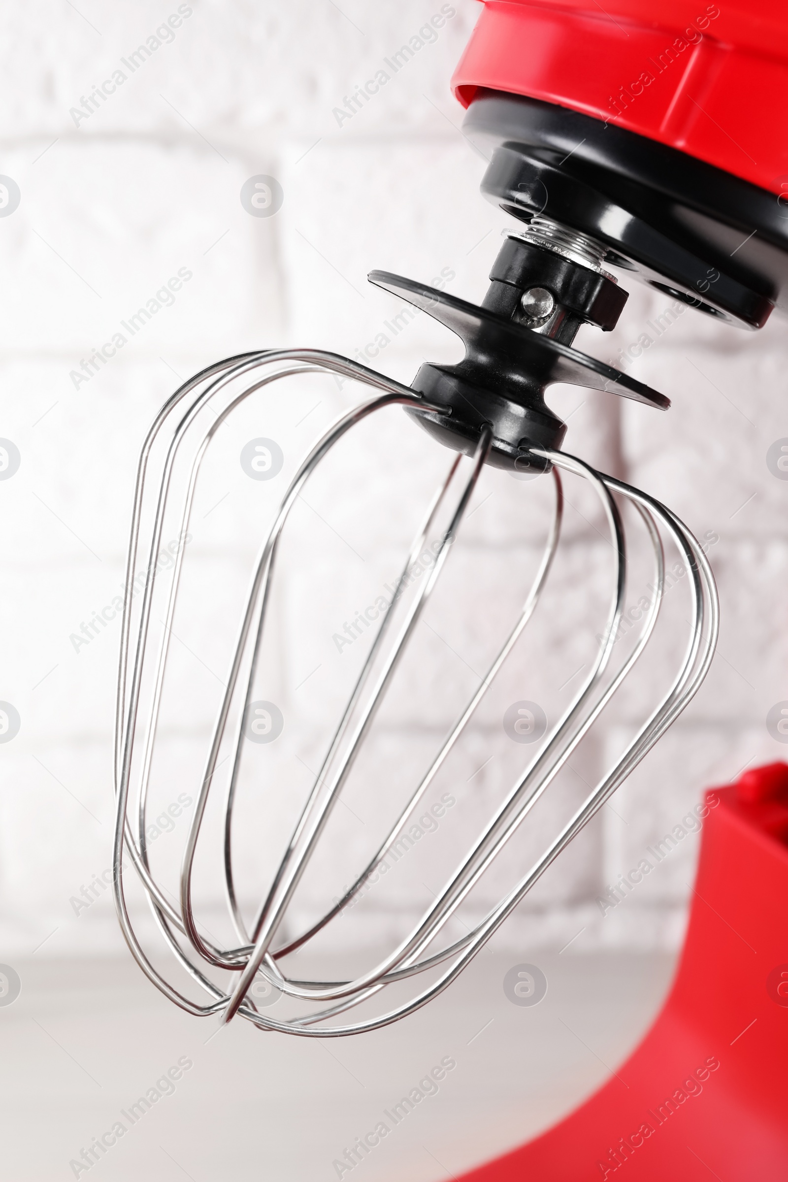 Photo of Modern red stand mixer near white brick wall, closeup