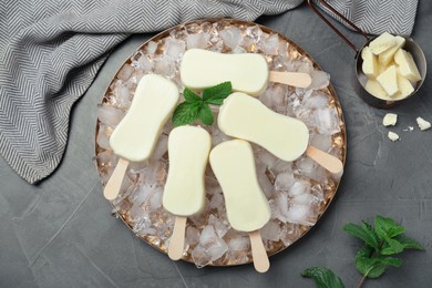 Photo of Flat lay composition with glazed ice cream bars, fresh mint and chocolate on grey table