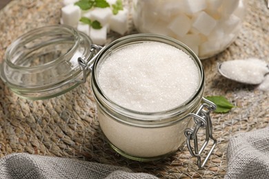 Photo of Jar of white sugar on wicker mat, closeup