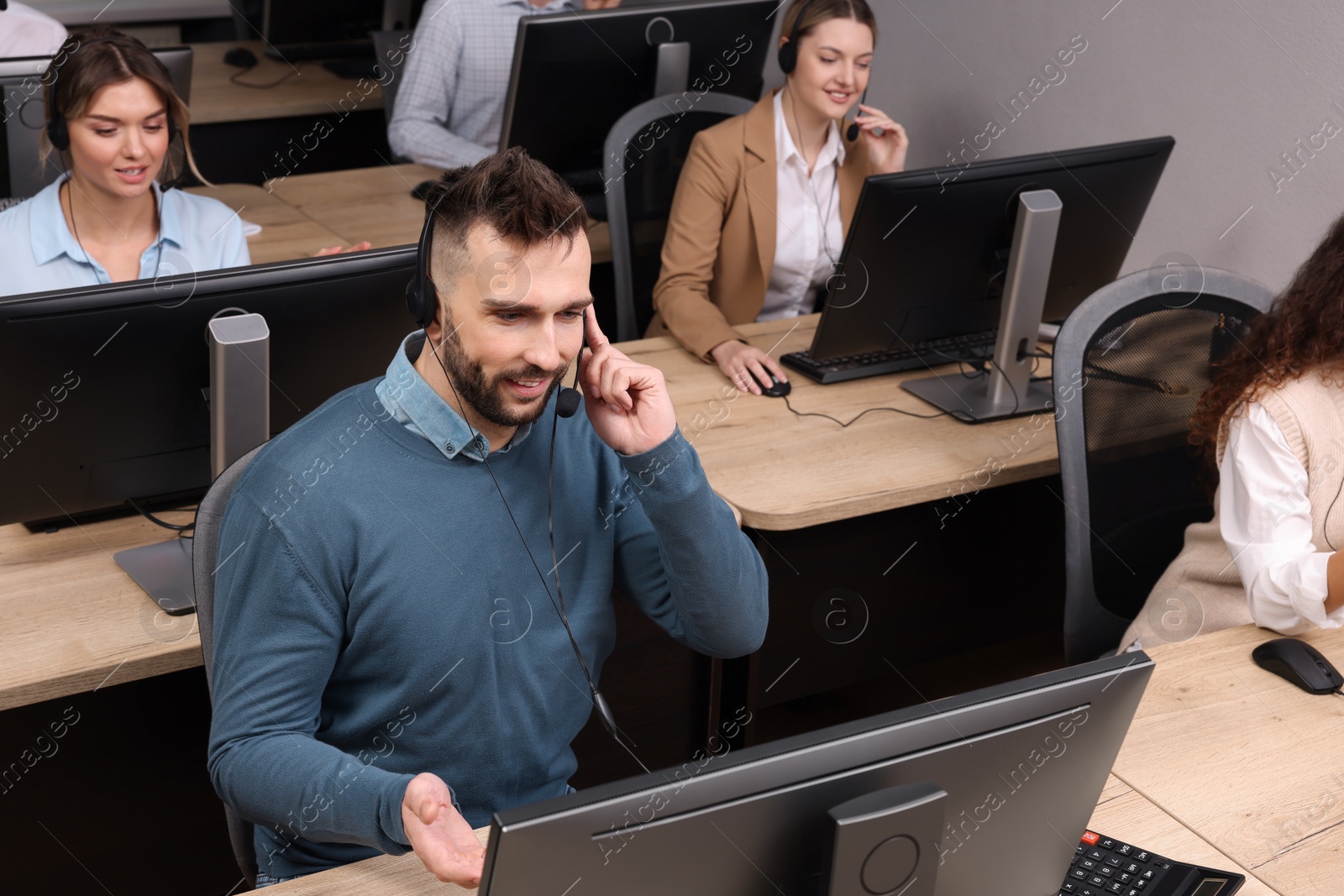 Photo of Call center operators with headsets working in modern office