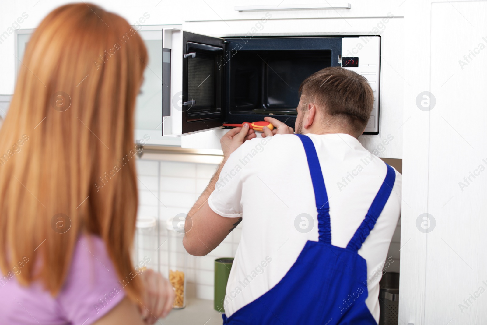 Photo of Housewife and repairman near microwave oven in kitchen