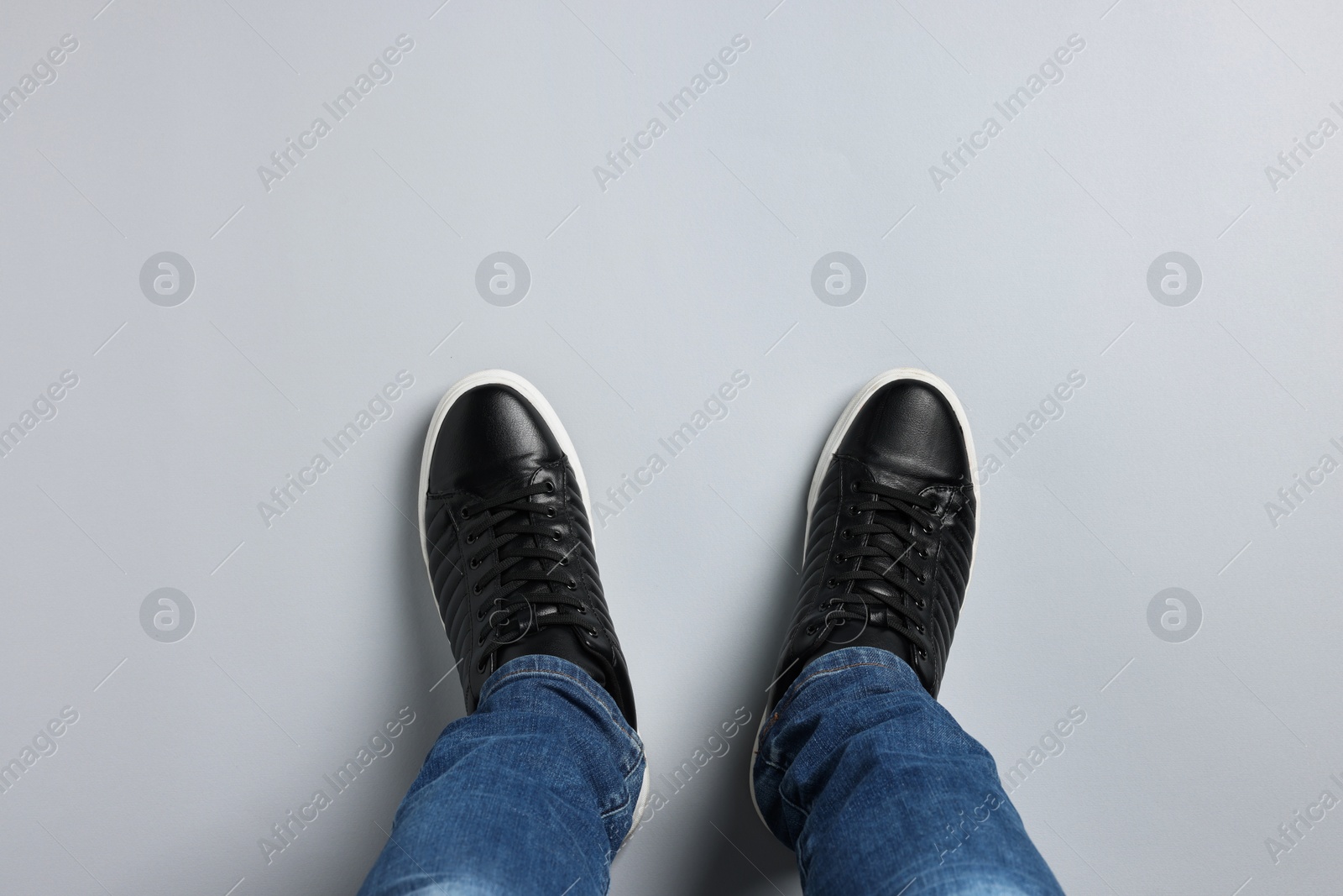 Photo of Man in stylish sneakers standing on light background, top view