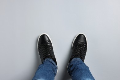 Photo of Man in stylish sneakers standing on light background, top view