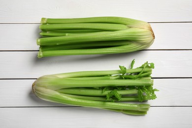 Fresh celery bunches on white wooden table, flat lay