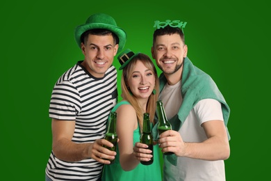 Happy people in St. Patrick's Day outfits with beer on green background