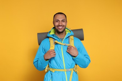 Happy tourist with backpack on yellow background