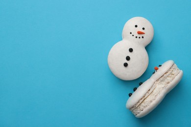 Photo of Beautiful snowman Christmas macarons on light blue background, flat lay. Space for text