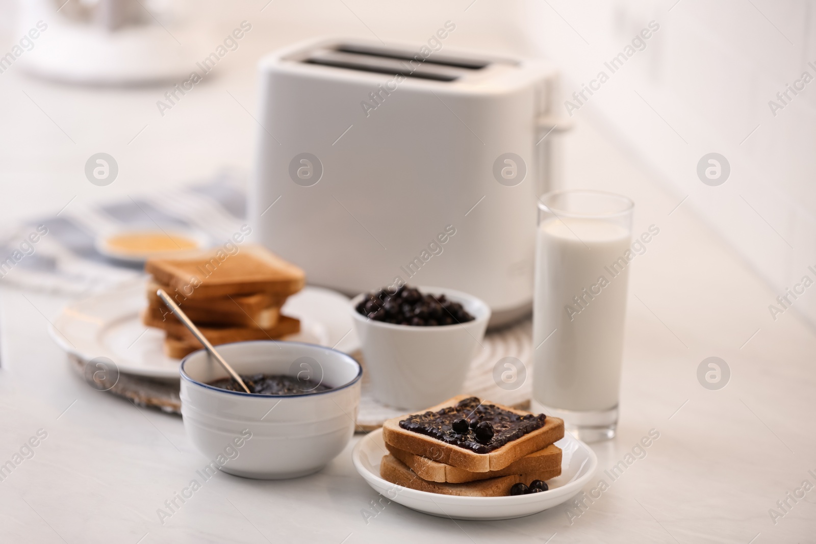 Photo of Modern toaster and delicious breakfast on table in kitchen