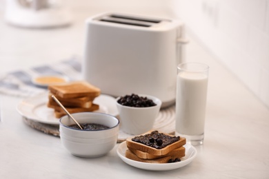 Photo of Modern toaster and delicious breakfast on table in kitchen