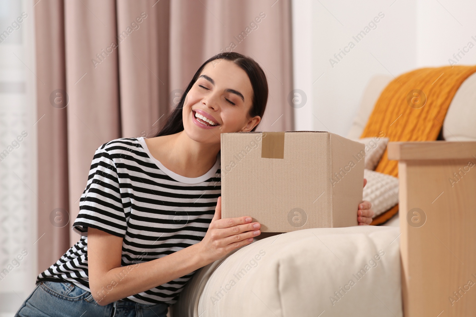 Photo of Happy young woman with parcel at home. Internet shopping