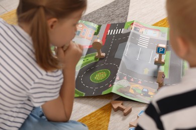 Photo of Little children playing with set of wooden road signs and toy cars indoors, selective focus