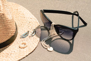 Stylish hat, sunglasses and jewelry on grey surface, closeup