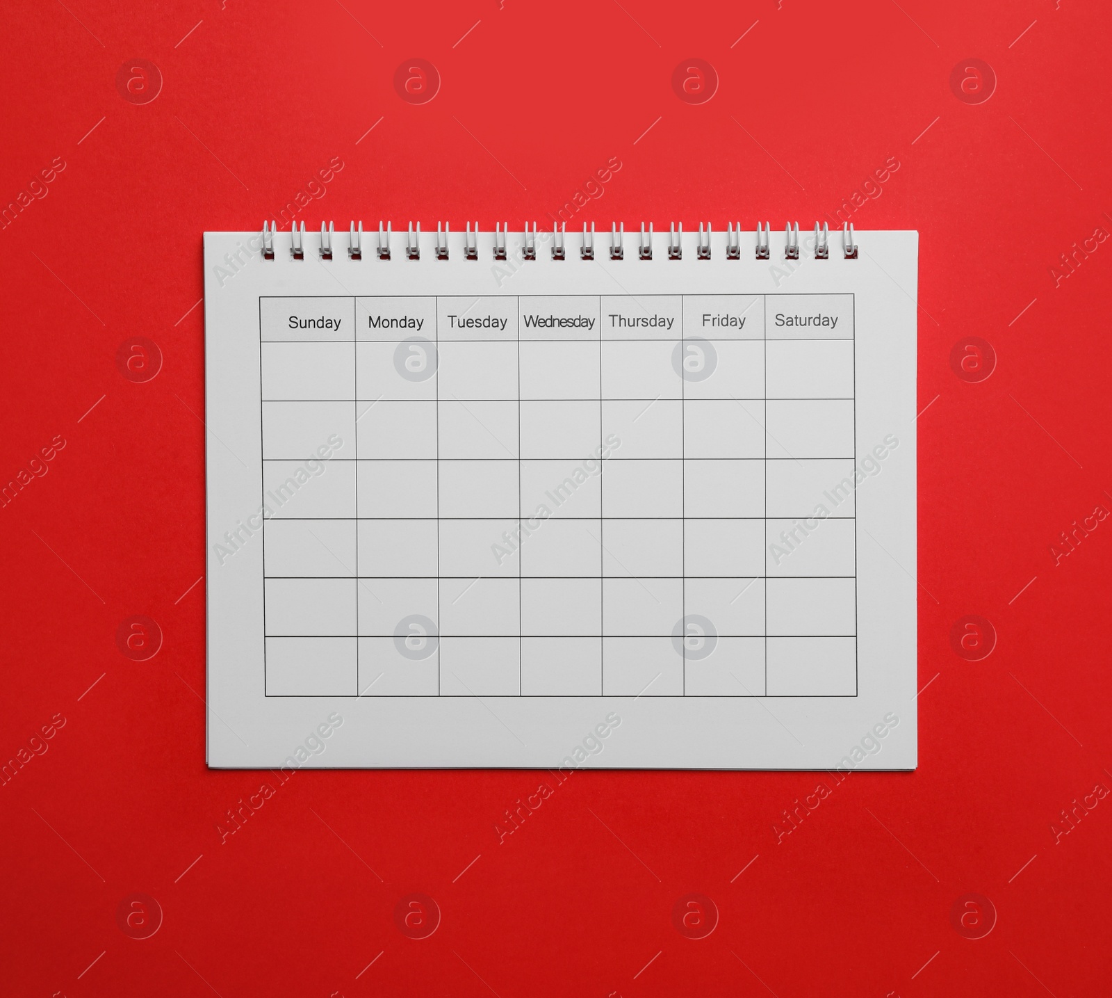 Photo of Blank calendar on red background, top view