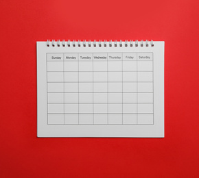 Photo of Blank calendar on red background, top view