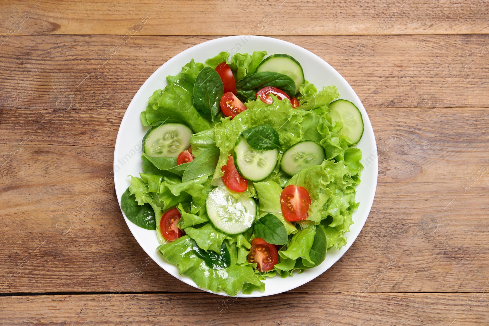 Photo of Delicious salad in bowl on wooden table, top view