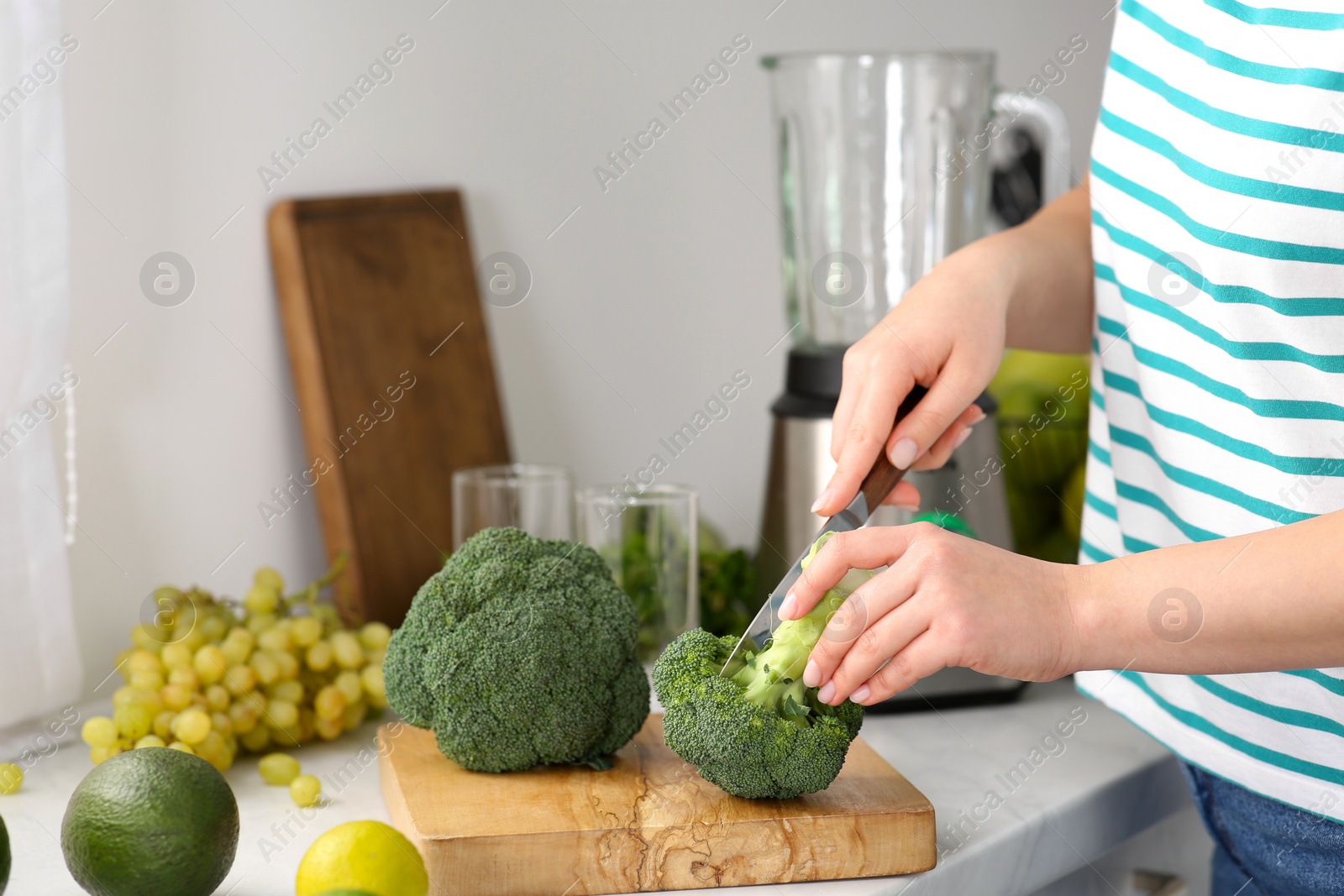 Photo of Woman cutting broccoli for smoothie in kitchen, closeup