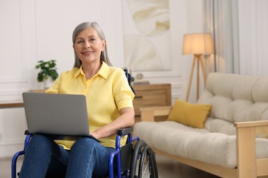 Woman in wheelchair using laptop at home