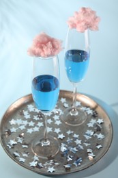 Photo of Cotton candy cocktails in glasses and confetti on light blue background, closeup