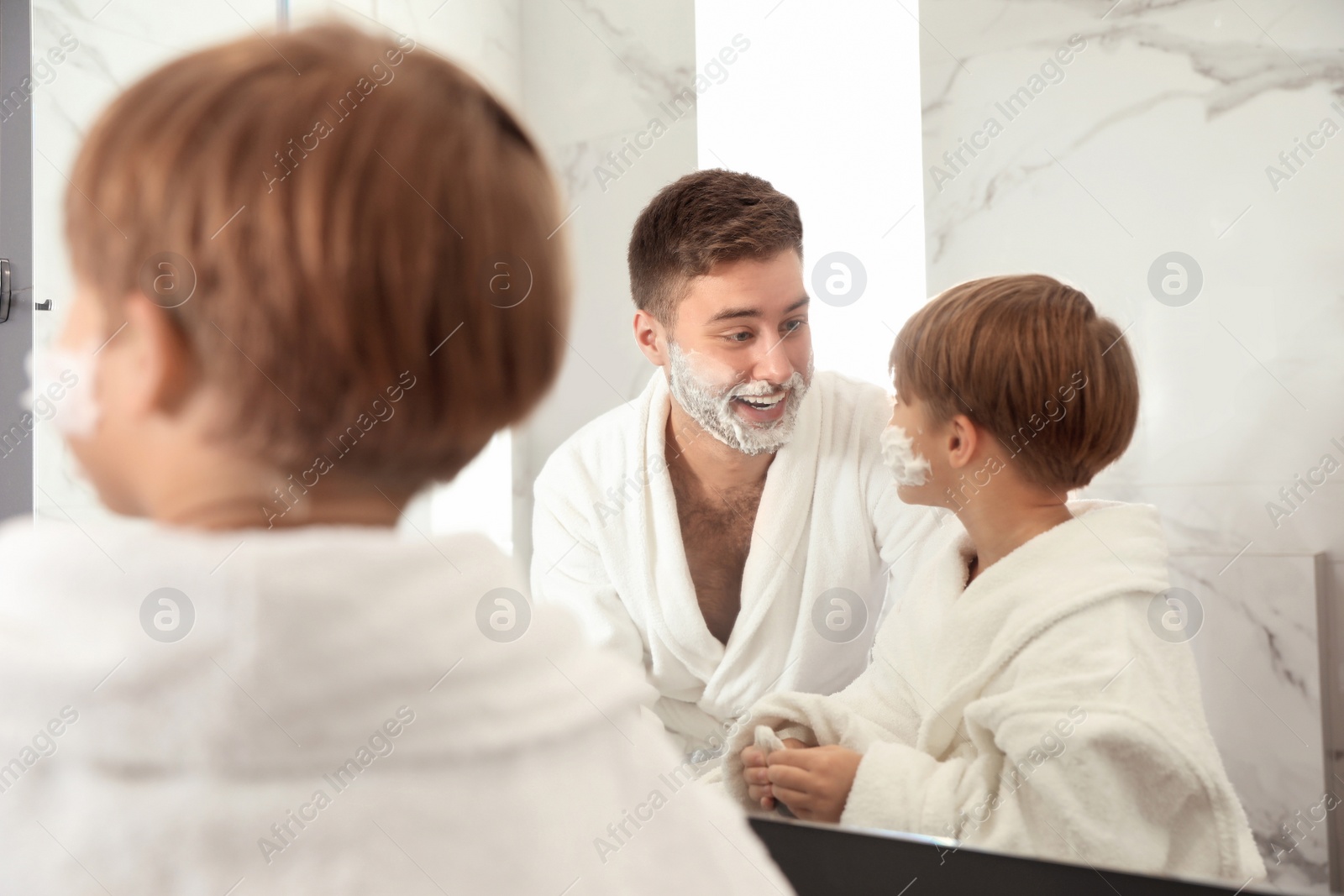 Photo of Dad and son with shaving foam on faces in bathroom