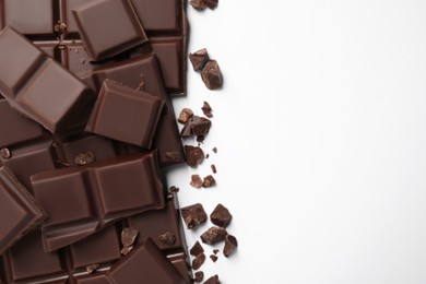 Photo of Pieces of delicious dark chocolate bars on white background, flat lay. Space for text