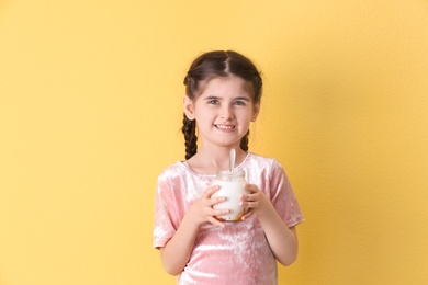 Little girl with yogurt on color background