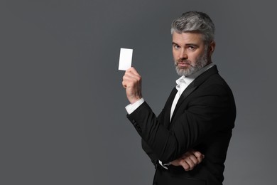 Photo of Handsome businessman holding blank business card on grey background. Space for text