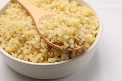 Photo of Delicious bulgur served on white table, closeup