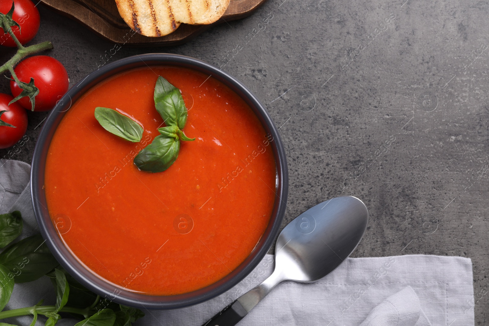 Photo of Flat lay composition with delicious tomato cream soup in bowl on grey textured table. Space for text