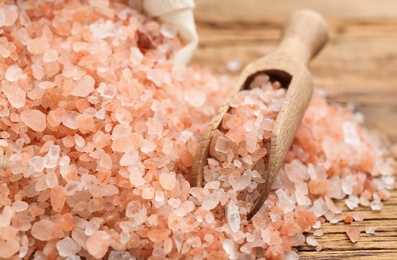 Photo of Scoop and pink himalayan salt on wooden table, closeup