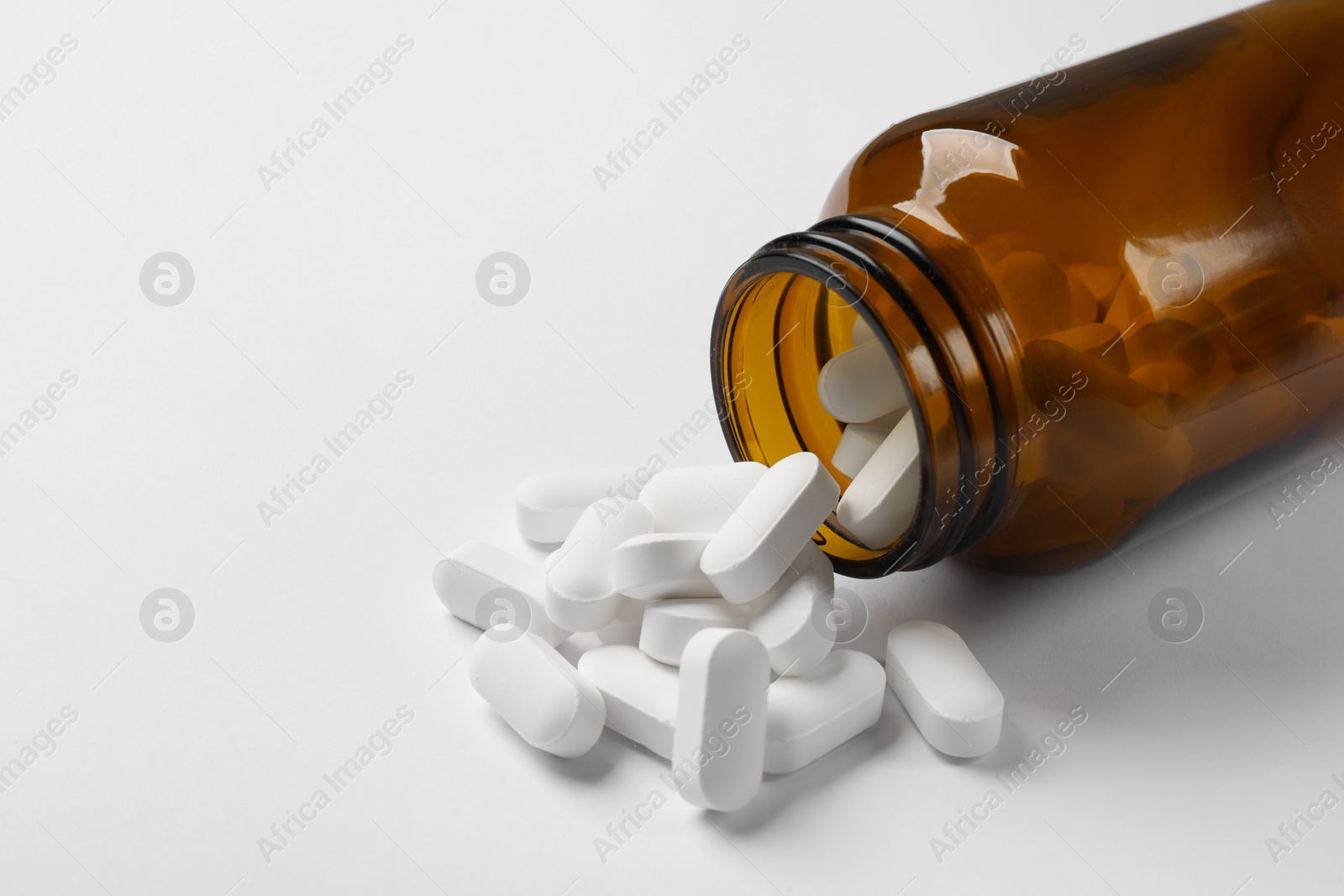 Photo of Bottle and vitamin capsules on white background, closeup. Space for text