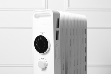 Photo of Modern portable electric heater near white wall, closeup