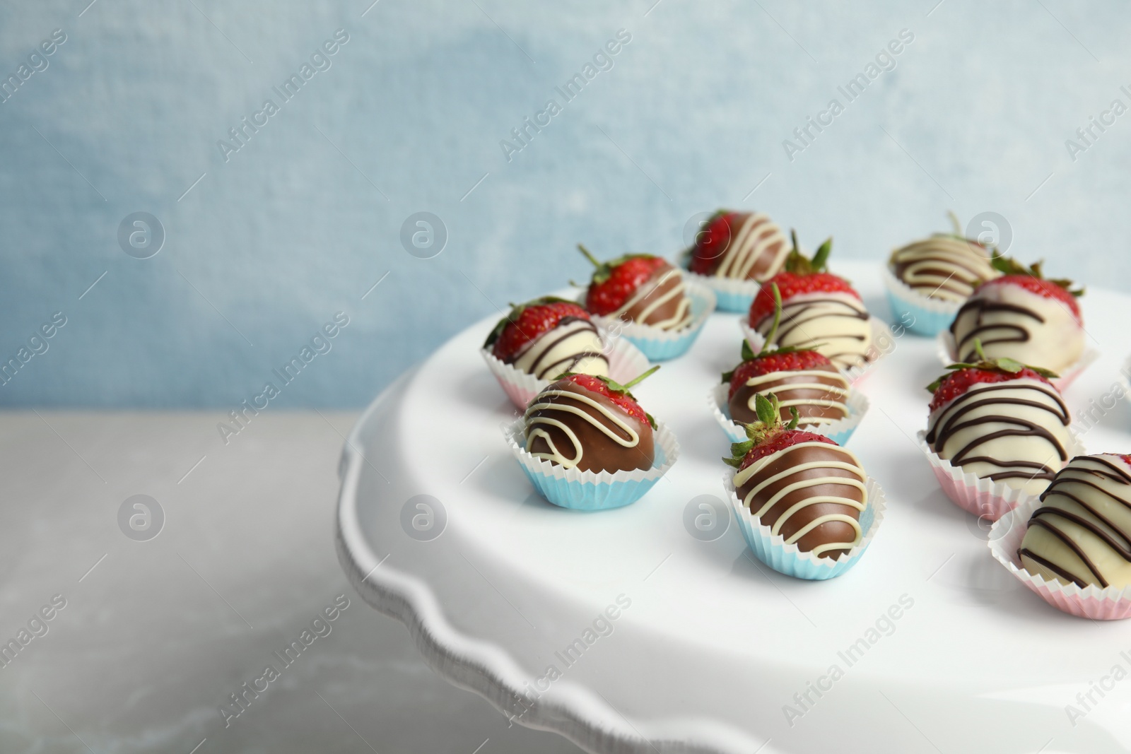 Photo of Dessert stand with chocolate covered strawberries on table, closeup