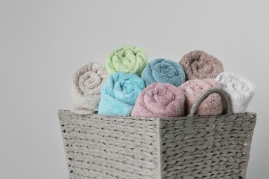 Photo of Wicker basket with clean soft towels on light background