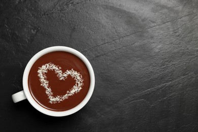 Cup of hot chocolate with heart shaped decoration on black table, top view. Space for text