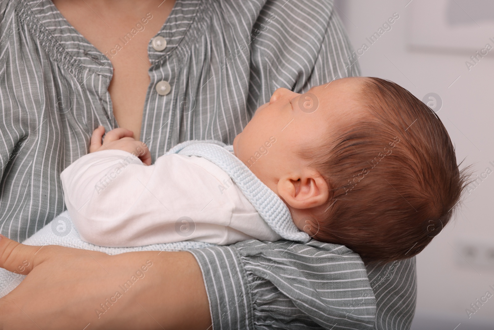 Photo of Mother holding her cute newborn baby on blurred background, closeup